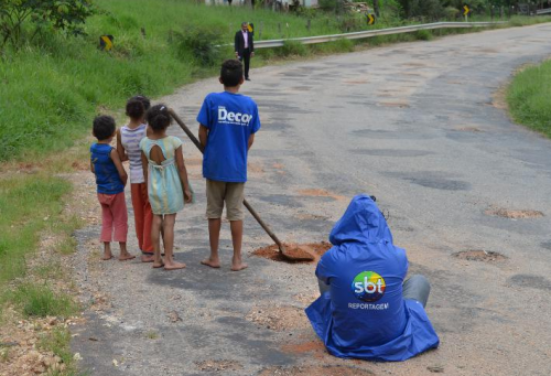 Crianças são flagradas tapando buracos na estrada